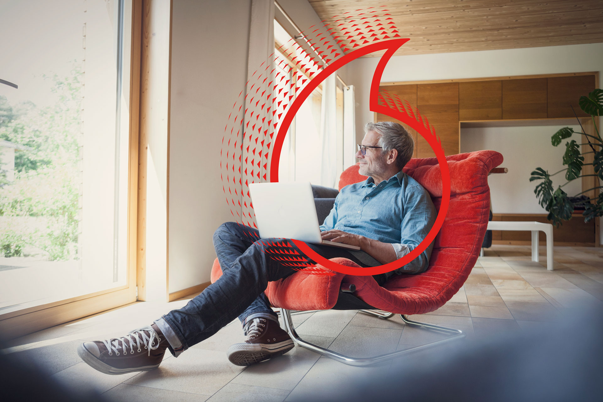 man sitting in chair with laptop on its lap starring out of the window